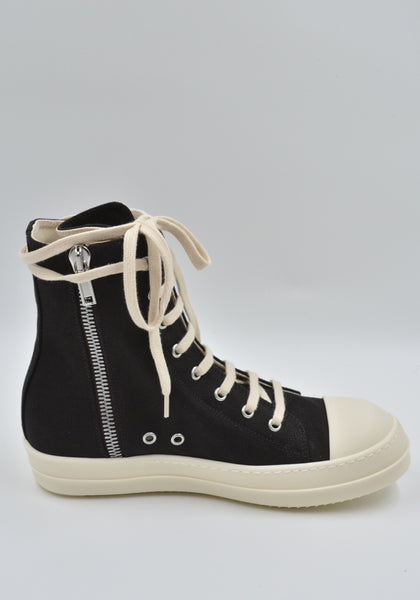 Cargo sneakers featuring a black cotton denim upper, above ankle height, eight eyelets, shoe lace, zipped cargo side pockets, milk white leather toe caps and shark tooth rubber soles